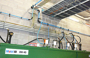 Oil and grease pumps connected to main lubrication supply tanks and high pressure lines in Auto workshop