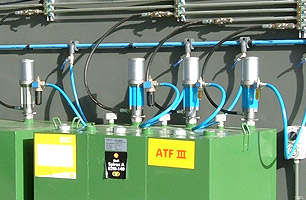 Lubrication tanks outside automotive workshop showing pumps feeding into main high pressure lines