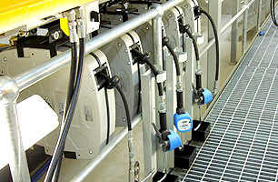 Encased lubrication hose reels mounted to roof of suspended ceiling workshop pit showing dispensers along side pit opening